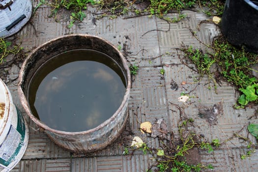 Photo a container with rainwater in the country after the rain. Mud.Plastic bucket and paving slabs.
