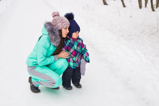 happy mother and baby in winter park. family outdoors. cheerful mommy with her child.