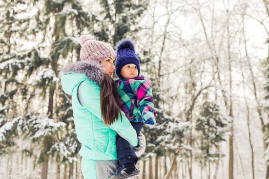 happy family mother and baby girl daughter playing and laughing in winter outdoors in the snow