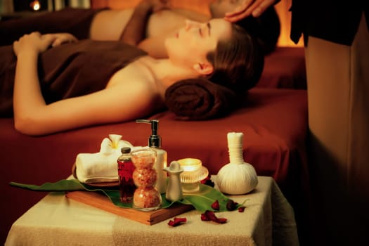 Aromatherapy massage ambiance or spa salon composition setup with focus decor candles and spa accessories on blur couple enjoying blissful aroma spa massage in resort or hotel background. Quiescent