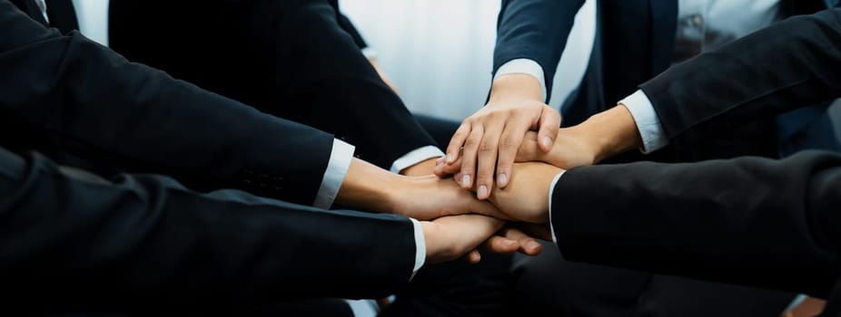 Office worker team stacking hand together symbolize successful group of business partnership and strong collective unity teamwork in community workplace in panoramic banner. Shrewd