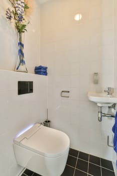 a white bathroom with blue towels and flowers on the wall above the toilet in front of the sink is next to it