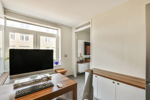 a living room with a tv, desk and computer monitor on the wall in front of the television is visible