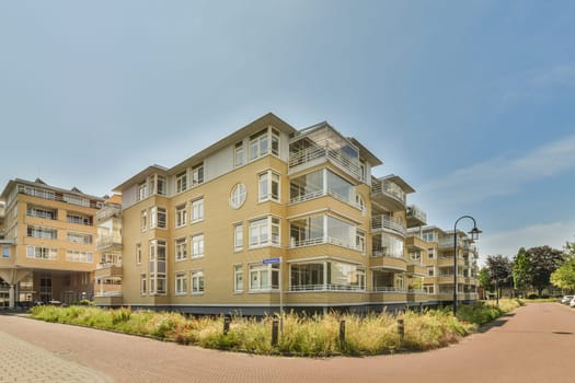 an apartment building in the daytime time with blue sky and white clouds above it, as seen from across the street