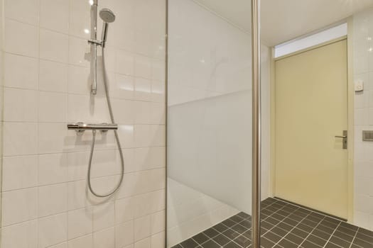 a shower room with tiled floor and white tiles on the walls there is a glass door to the left side