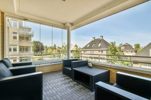 an outside area with couches, tables and chairs looking out onto the street in front of the apartment building