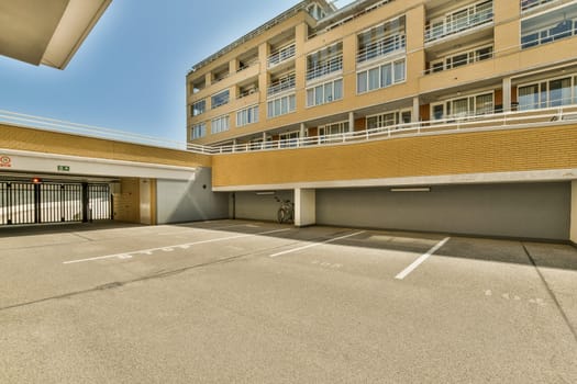 an empty parking area in front of a large brick building with white lines painted on the ground and two garages
