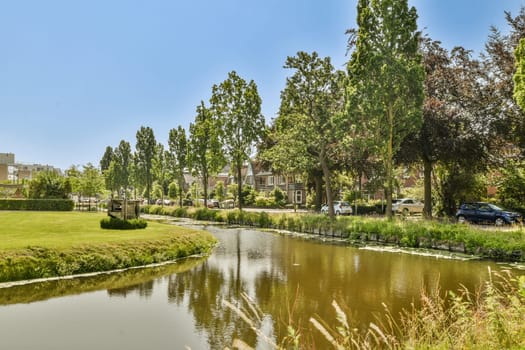 a small river in the middle of a residential area with houses and trees on either side of the stream, surrounded by lush green grass