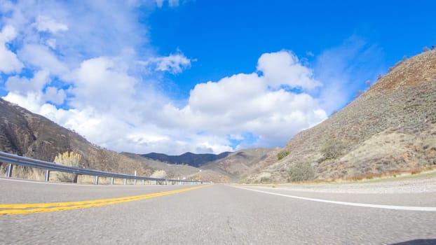 Vehicle is cruising along the Cuyama Highway under the bright sun. The surrounding landscape is illuminated by the radiant sunshine, creating a picturesque and inviting scene as the car travels through this captivating area.