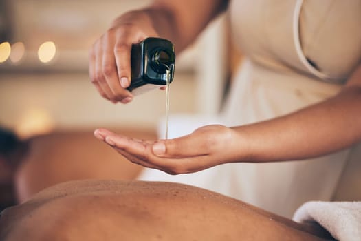 Masseuse, hands and oil for back massage, relax or lubricant in salon or spa treatment at resort. Closeup of female person pouring liquid for body care, physical therapy or healing in zen at hotel.
