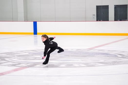 Little girl practicing figure skating at the indoor ice rink.