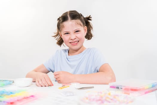 Little girl enjoys crafting colorful bracelets with vibrant clay beads set.