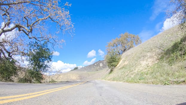 Vehicle is cruising along the Cuyama Highway under the bright sun. The surrounding landscape is illuminated by the radiant sunshine, creating a picturesque and inviting scene as the car travels through this captivating area.