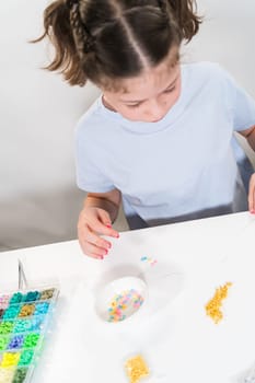 Little girl enjoys crafting colorful bracelets with vibrant clay beads set.