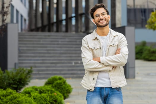 Portrait of happy Indian man smiling friendly, glad expression looking at camera dreaming, resting relaxation feel satisfied good news outdoors. Arabian guy in city street. Business people. Copy-space