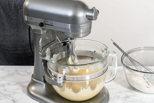 Mixing ingredients in kitchen electric mixer to bake American flag mini cupcakes.