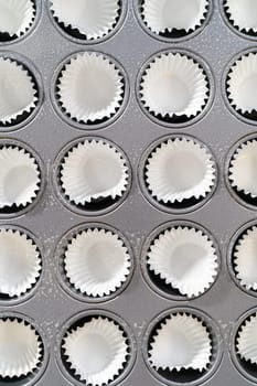 Scooping cupcake batter with dough scoop into a baking pan with liners to bake American flag mini cupcakes.