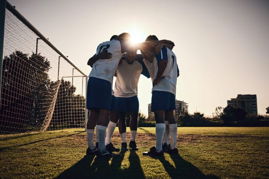 Soccer, sunset or team in a huddle for motivation, goals or group mission on stadium field for a sports game. Match, sunshine or football players planning a strategy, exercise or training for fitness.