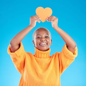 Portrait, emoji and heart with a black woman on blue background in studio for health or wellness. Smile, love and social media with a happy young person looking excited for romance or valentines day.