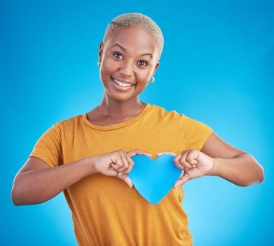 Portrait, love and heart with a black woman on blue background in studio for health or wellness. Smile, emoji and social media with a happy young person looking excited for romance or valentines day.