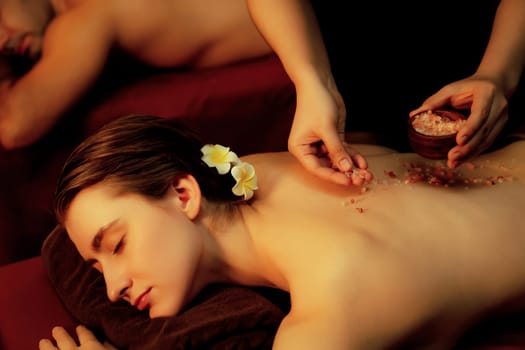 Couple customer having exfoliation treatment in luxury spa salon with warmth candle light ambient. Salt scrub beauty treatment in Health spa body scrub. Quiescent