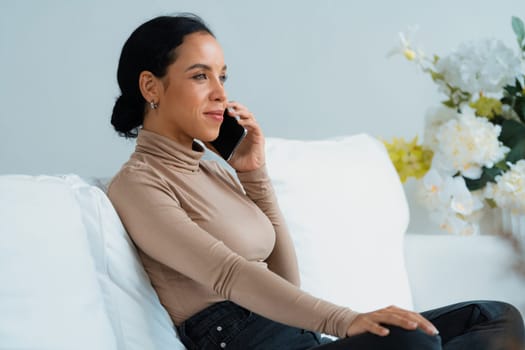 Relaxed young African American woman using crucial mobile phone on sofa couch in living room at home