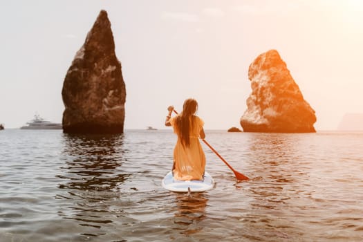 Close up shot of beautiful young caucasian woman with black hair and freckles looking at camera and smiling. Cute woman portrait in a pink bikini posing on a volcanic rock high above the sea