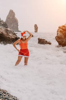 Woman travel sea. Young Happy woman in a long red dress posing on a beach near the sea on background of volcanic rocks, like in Iceland, sharing travel adventure journey