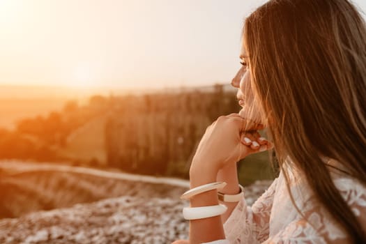 Romantic beautiful bride in white dress posing with sea and mountains in background. Stylish bride standing back on beautiful landscape of sea and mountains on sunset