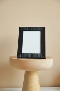 Black frame mockup on table against white wall