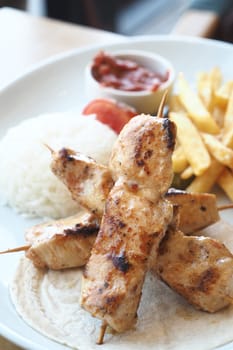 Chicken skewers with french fries and rice ,