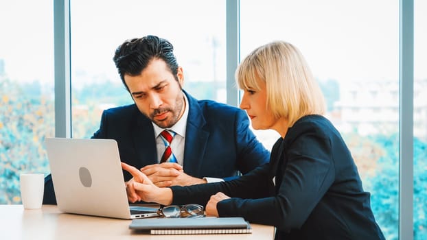 Two business people talk project strategy at office meeting room. Businessman discuss project planning with colleague at modern workplace while having conversation and advice on financial report. Jivy