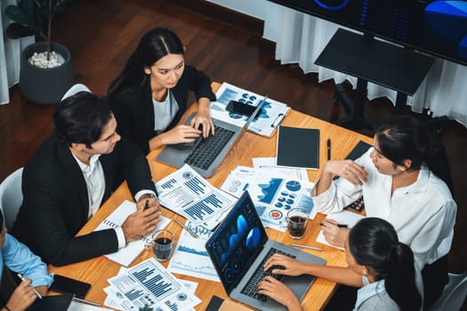 Wide top view of diverse group of business analyst team analyzing financial data report paper on meeting table. Chart and graph dashboard by business intelligence analysis. Meticulous