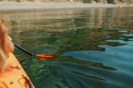 Kayak paddle sea vacation. Person paddles with orange paddle oar on kayak in sea. Leisure active lifestyle recreation activity rest tourism travel.