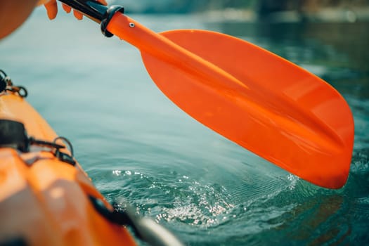 Kayak paddle sea vacation. Person paddles with orange paddle oar on kayak in sea. Leisure active lifestyle recreation activity rest tourism travel.