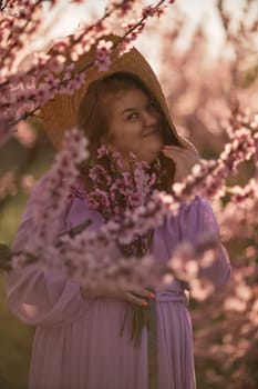 Woman blooming peach orchard. Against the backdrop of a picturesque peach orchard, a woman in a long pink dress and hat enjoys a peaceful walk in the park, surrounded by the beauty of nature