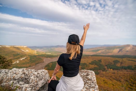 woman on mountain peak looking in beautiful mountain valley in autumn. Landscape with sporty young woman, blu sky in fall. Hiking. Nature.