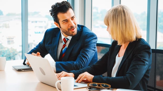 Two business people talk project strategy at office meeting room. Businessman discuss project planning with colleague at modern workplace while having conversation and advice on financial report. Jivy