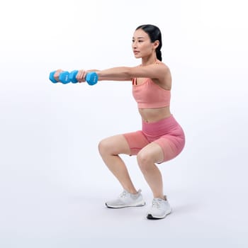 Vigorous energetic woman doing dumbbell weight lifting exercise on isolated background. Young athletic asian woman strength and endurance training session as body workout routine.