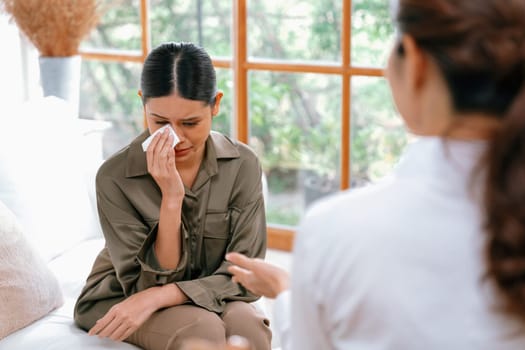 Sad PTSD woman patient in uttermost therapy for mental health with psychologist, depression or grief after life failure. Frustrated trauma young woman talking to a psychologist about emotion in clinic