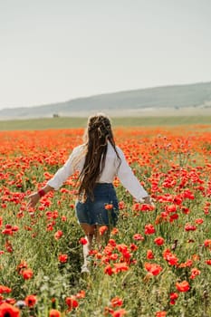 Woman poppies field. Back view of a happy woman with long hair in a poppy field and enjoying the beauty of nature in a warm summer day