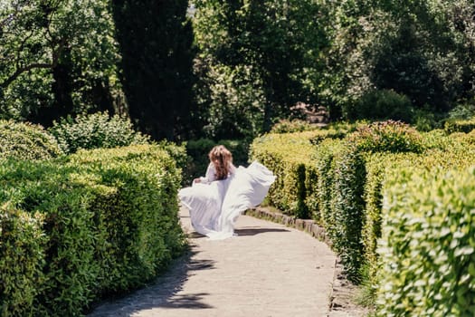 a beautiful woman with long brown hair runs along a path along beautiful bushes in the park