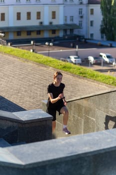 A young woman in black clothes running on stairs at city street early morning.