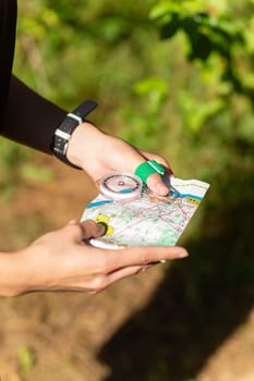 Woman holding a map and the compass during orienteering competitions. Athlete uses navigation equipment for orienteering,compass and topographic map.