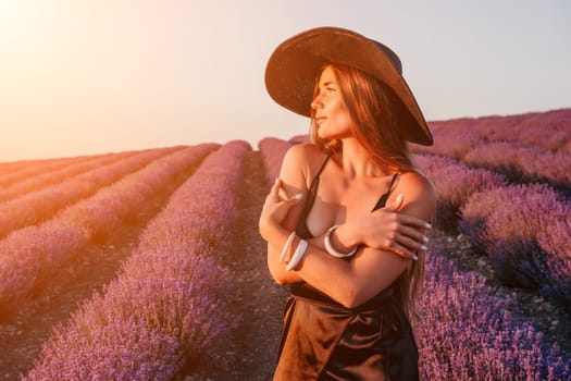 Close up portrait of young beautiful woman in a white dress and a hat is walking in the lavender field and smelling lavender bouquet.