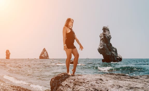 Woman travel sea. Young Happy woman in a long red dress posing on a beach near the sea on background of volcanic rocks, like in Iceland, sharing travel adventure journey