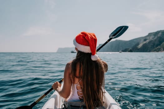 Woman in kayak back view. Happy young woman with long hair floating in transparent kayak on the crystal clear sea. Summer holiday vacation and cheerful female people relaxing having fun on the boat