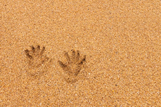 Prints of women's hands on golden sea sand. Sea holiday concept.