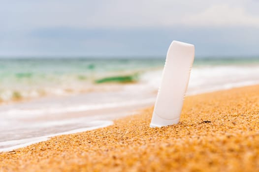 Bottle of sunscreen on the beach. sunburn lotion on the beach with the sparkling sea in the background and rolling waves. Close up of sunscreen cosmetic products.