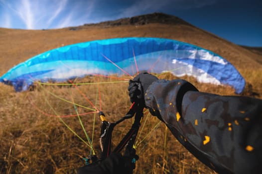 Point of view of a skydiver piloting his parachute. Hands holding the lines of their parachute, wide angle view.